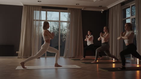 A-group-of-women-is-engaged-in-stretching-and-balance-with-an-instructor-in-a-beautiful-hall-with-large-windows.-Healthy-lifestyle-group-classes.-Women's-sports-club-slow-motion